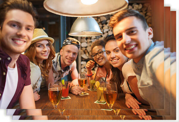 people, leisure, friendship, technology and party concept - group of happy smiling friends with smartphone and drinks taking selfie at bar or pub