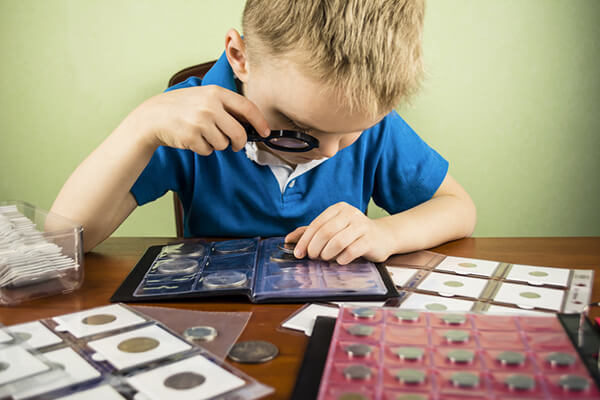 boy looking through a magnifying glass on a coin
